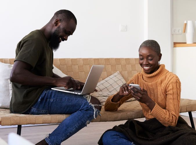 Man and woman smiling, on their laptops and phones