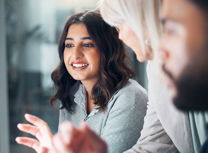 One support agent in focus while other agents gather around her computer