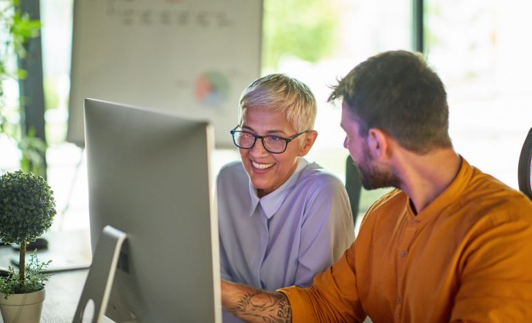 Two professionals talking in front of a computer monitor