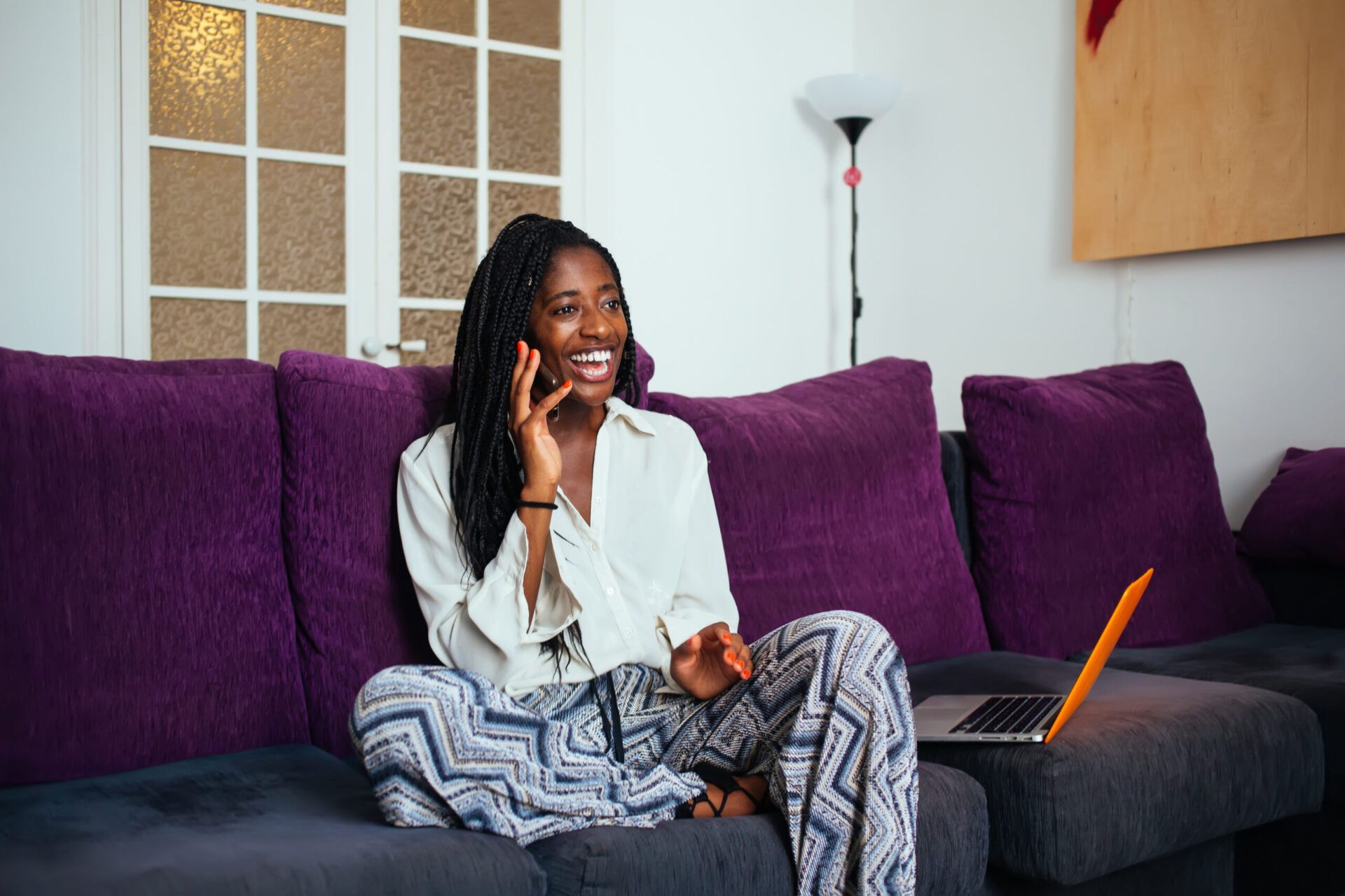 Woman sitting on couch, smiling while talking on cellphone 