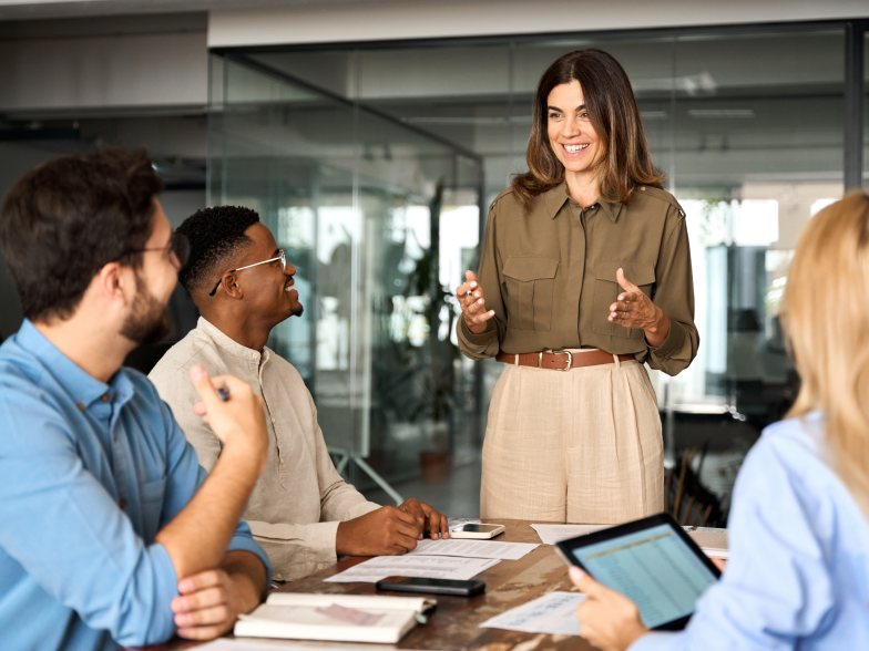 A customer experience leader standing to guide a team meeting while colleagues listen