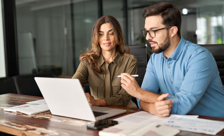 Two people having a discussion in front of a laptop