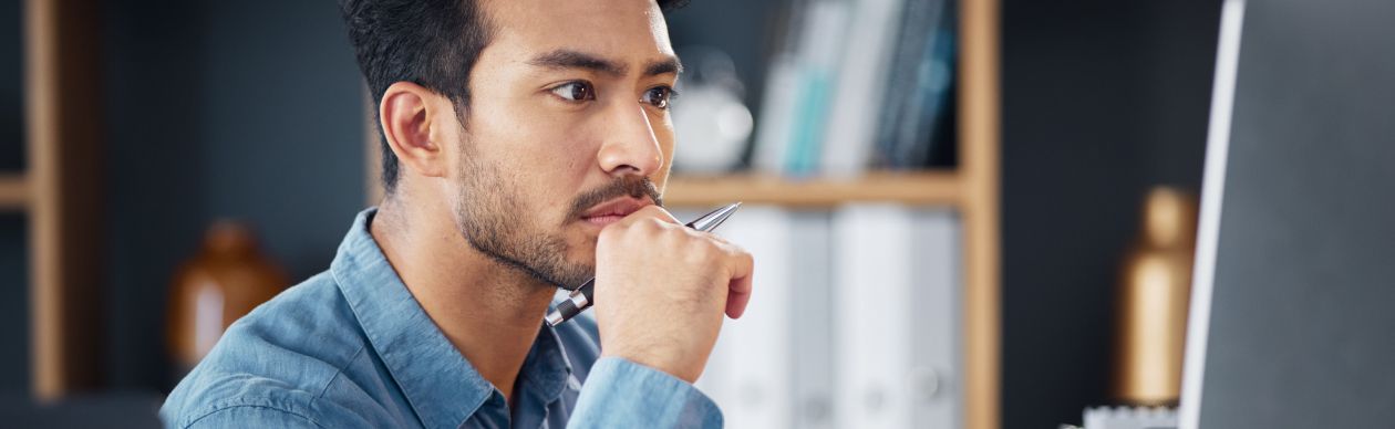 Man in a blue shirt looking seriously at his computer monitor