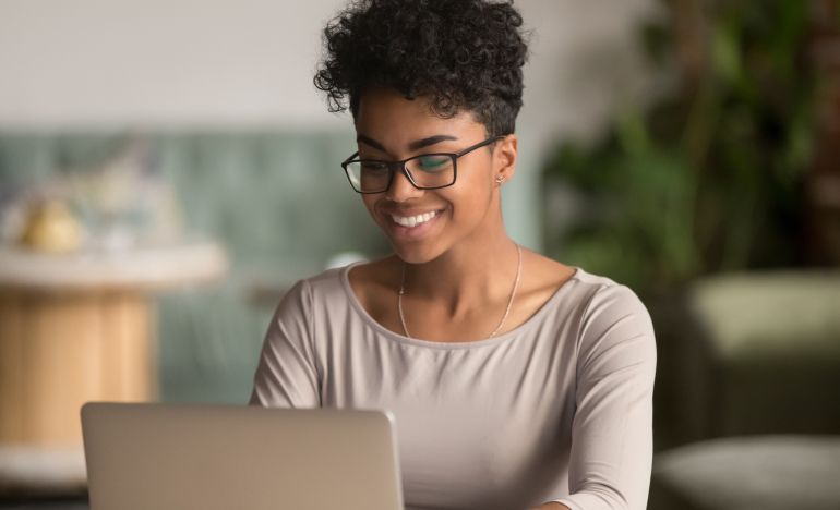 Bespectacled woman smiling down at her laptop