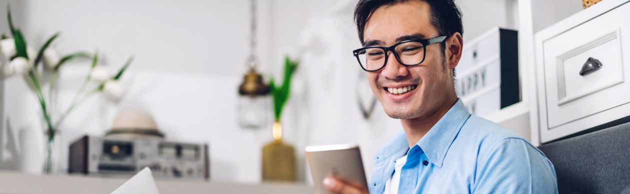 Man in glasses smiling at his smartphone