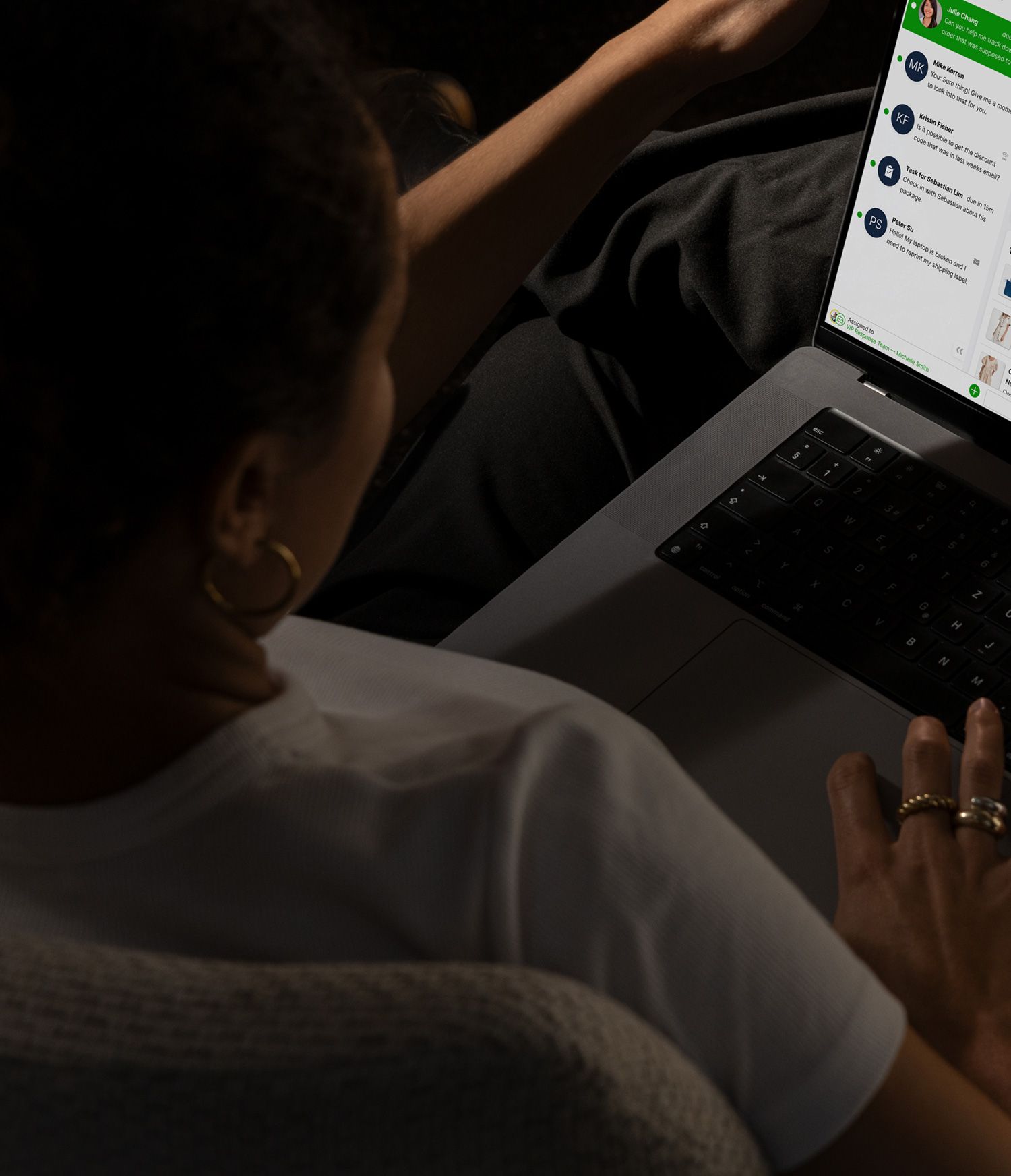 A person using a laptop with a customer service chat interface on the screen, surrounded by a potted plant, coffee cup, eyeglasses, and notepad.
