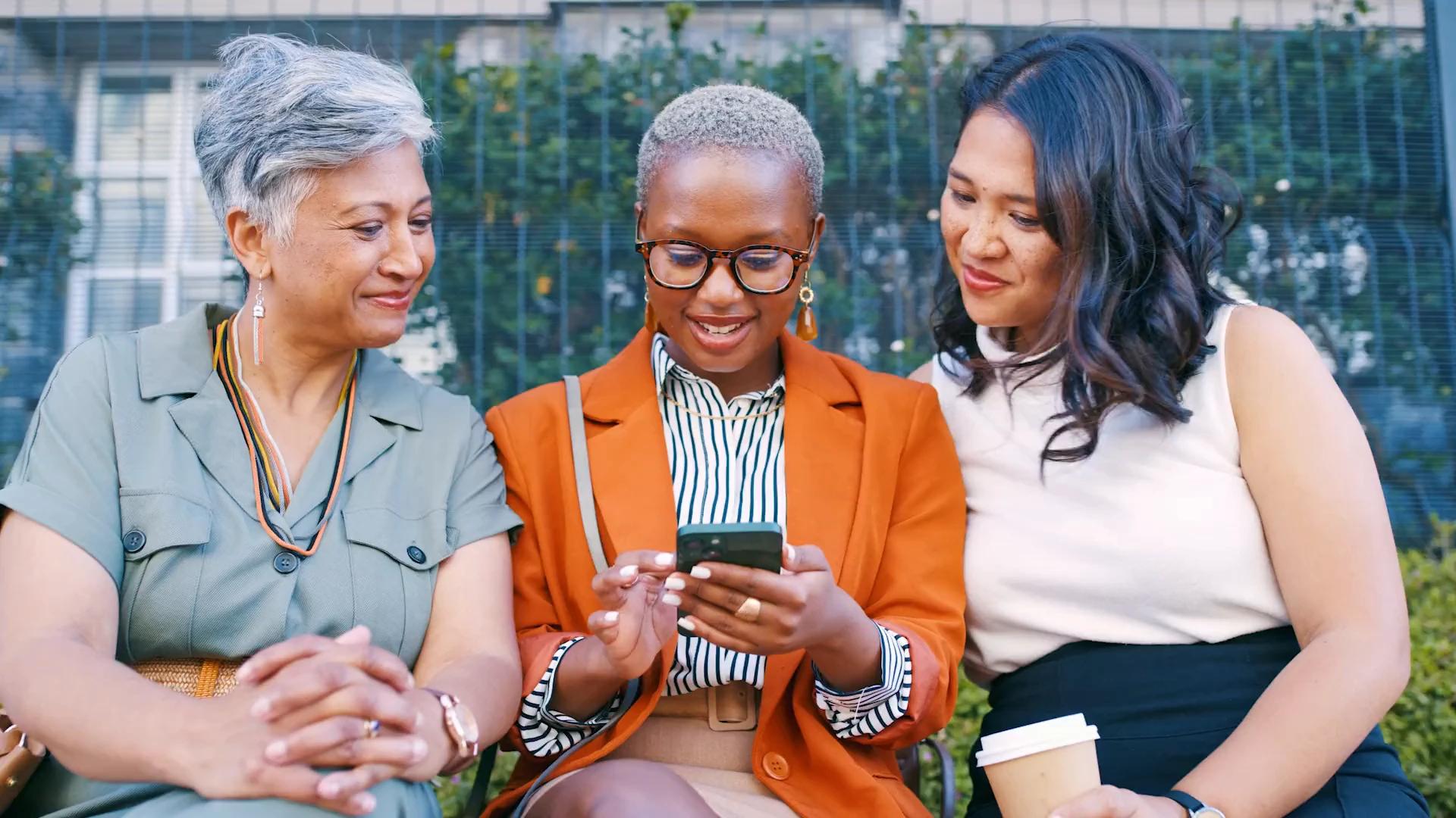 Three colleagues outdoors looking at a phone together