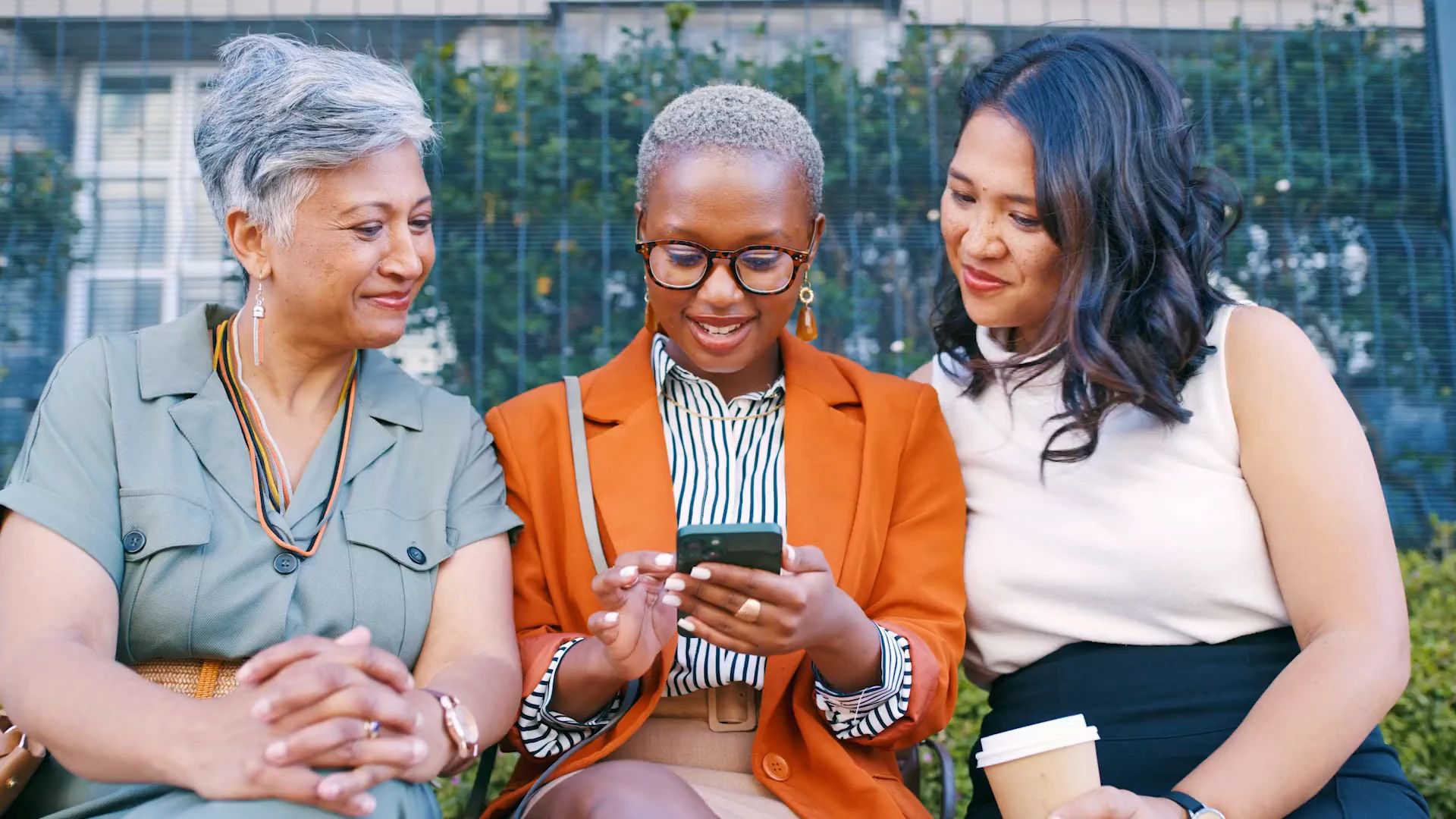 Three colleagues outdoors looking at a phone together