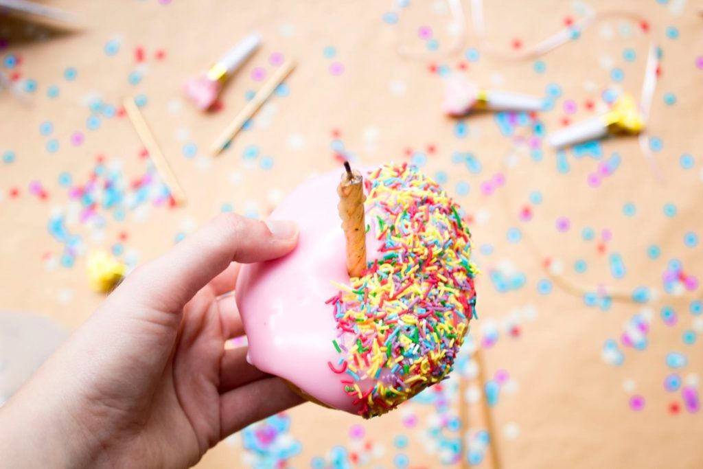 A hand holding a sprinkle donut