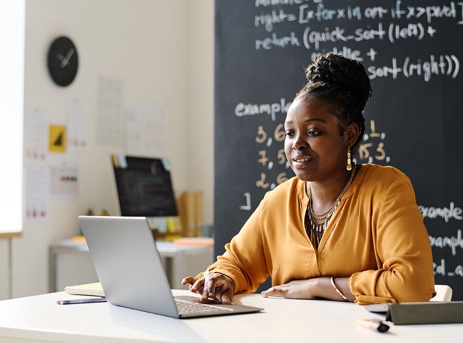 Teacher in classroom looking at laptop