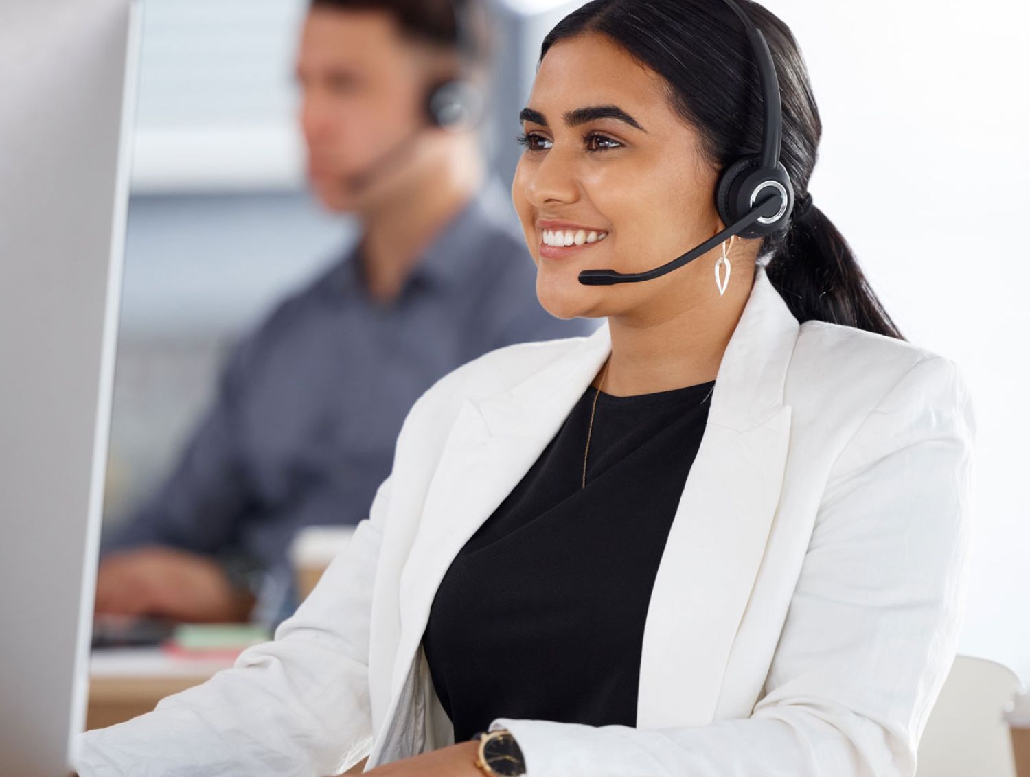 A woman customer service agent wearing a headset looking at computer