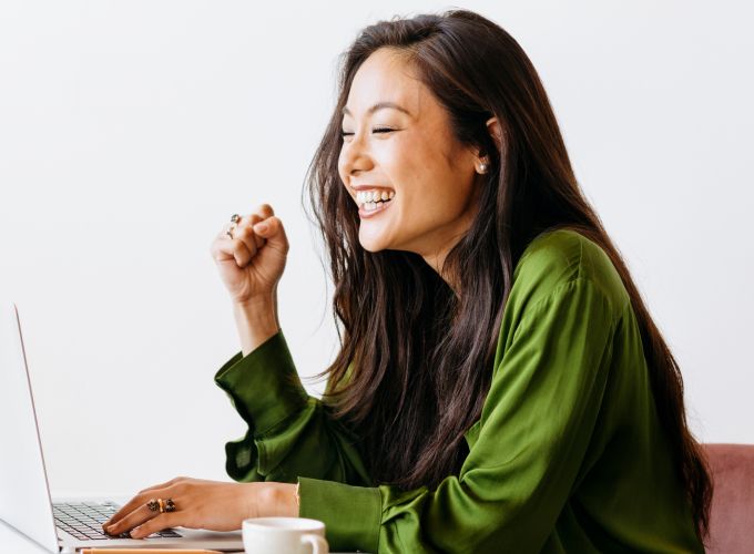 Woman at table with a vase full of flowers while on her laptop