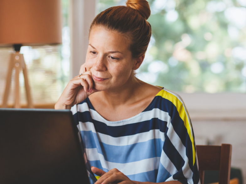 woman looking thoughtfully at laptop