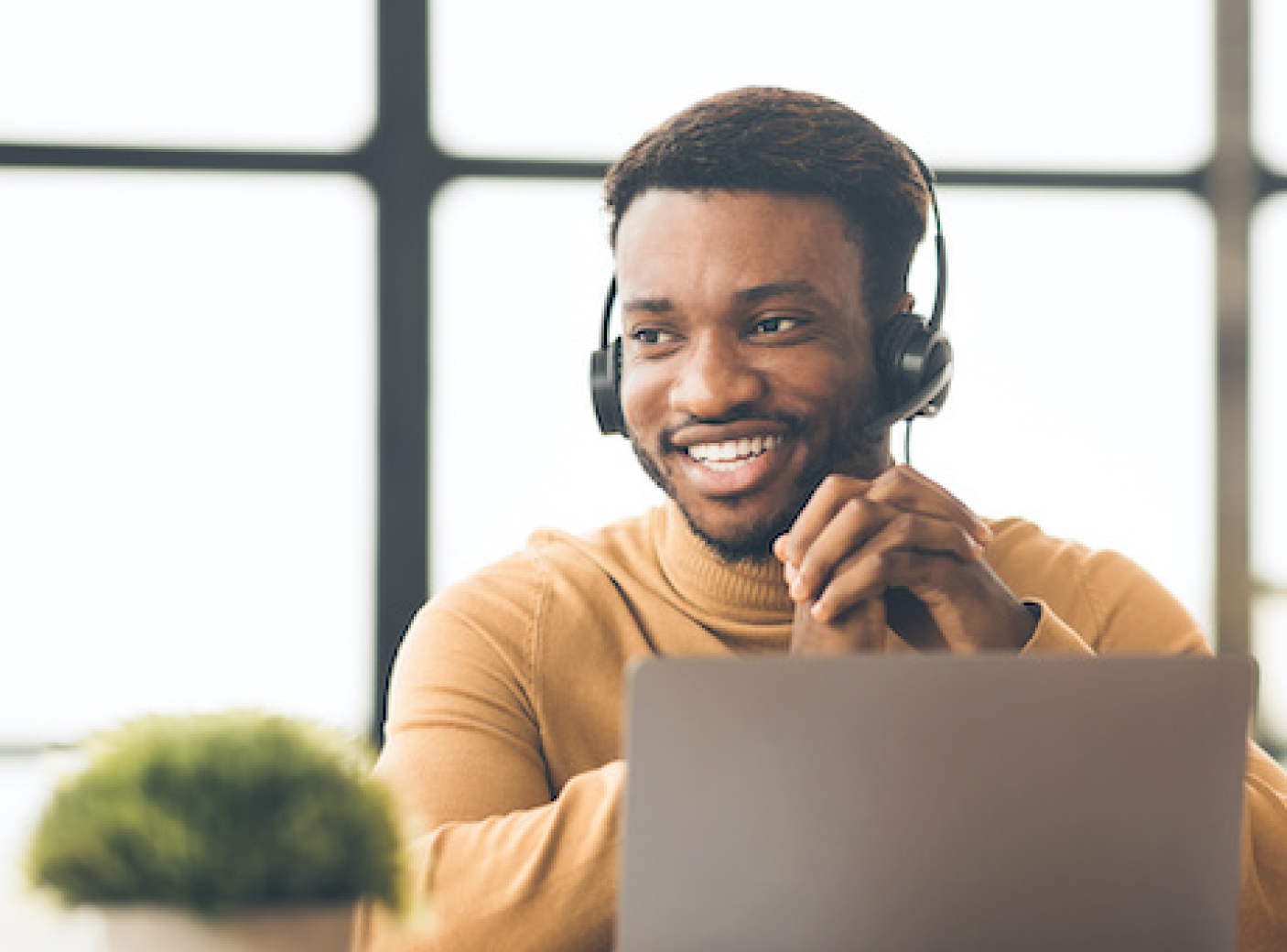 Man in an orange sweater smiling and wearing a phone headset