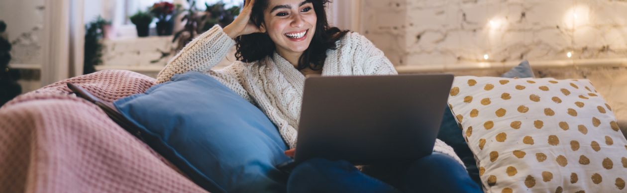 Smiling woman sitting on a couch with a laptop 