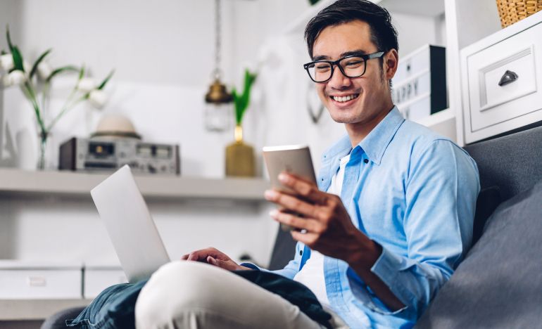 Man in glasses smiling at his smartphone