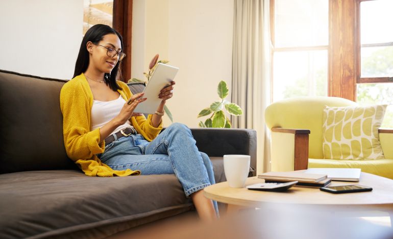 Woman relaxing on the couch in her living room looking at a tablet