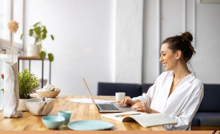 Woman in a white shirt looking at a laptop on a desk