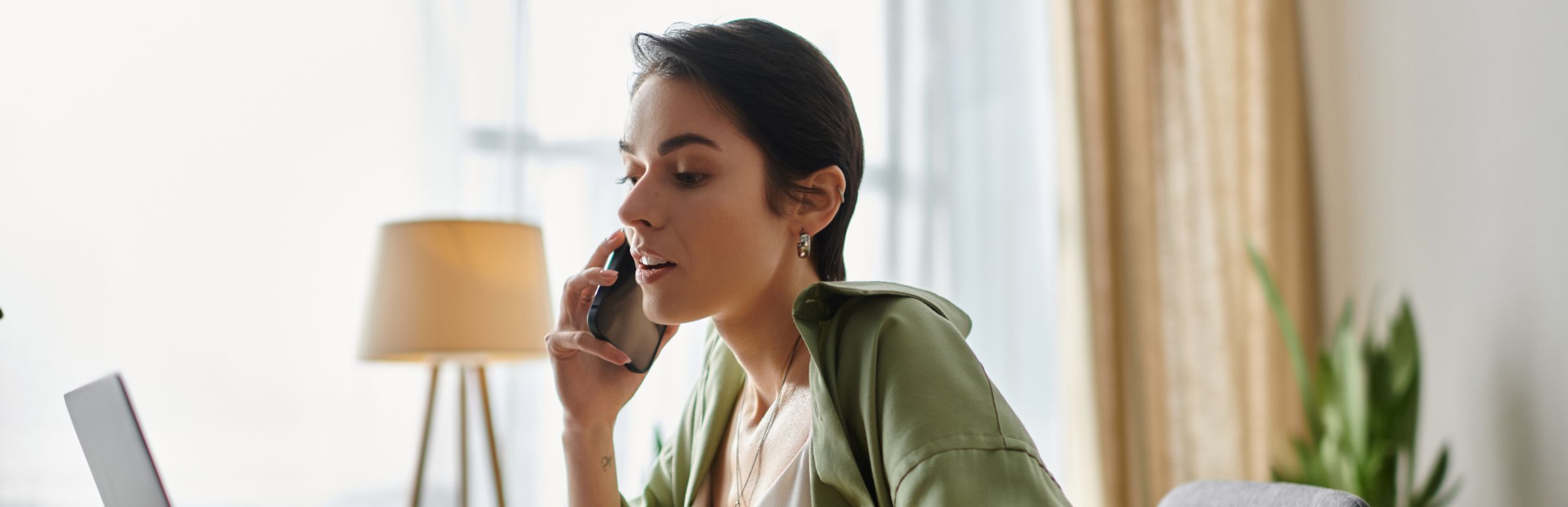 Woman on her phone reviewing her computer