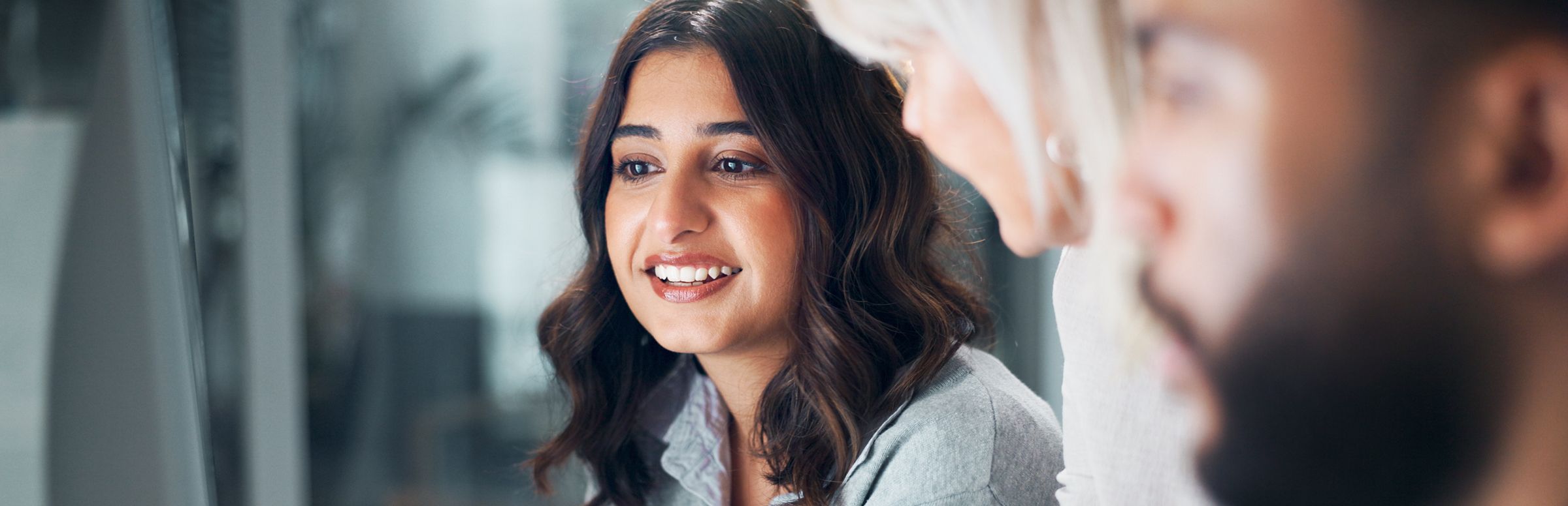 One support agent in focus while other agents gather around her computer