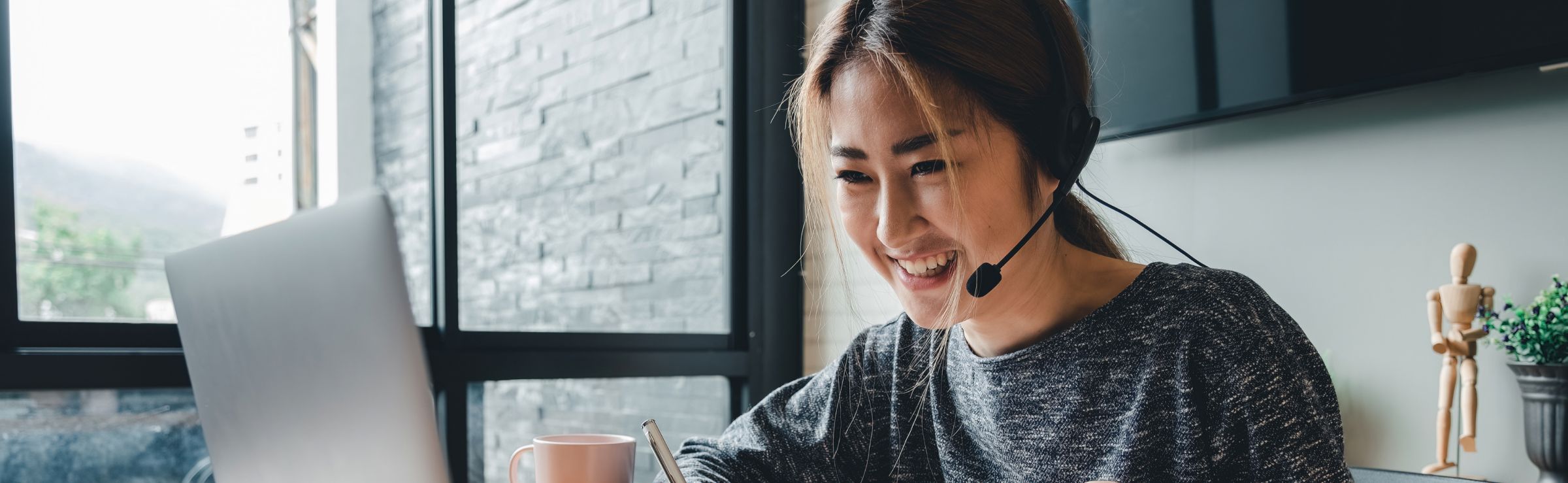 Customer support agent wearing headset while using her laptop