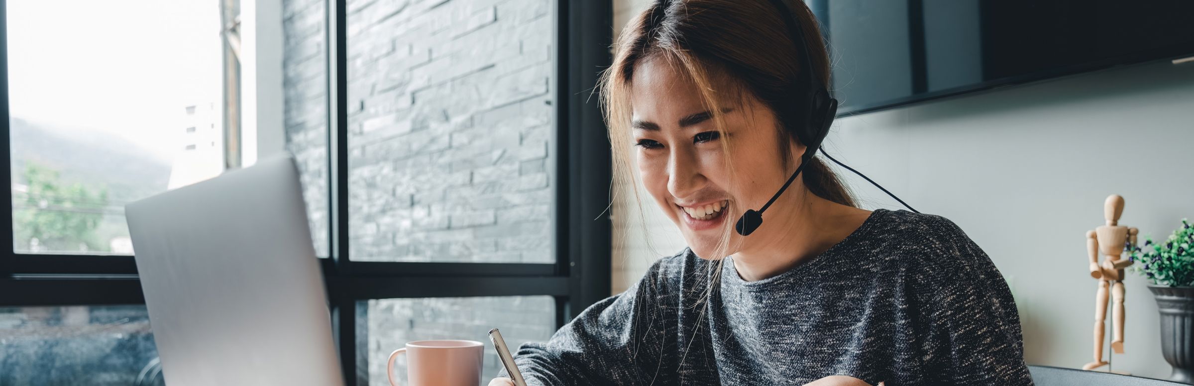 Customer support agent wearing headset while using her laptop