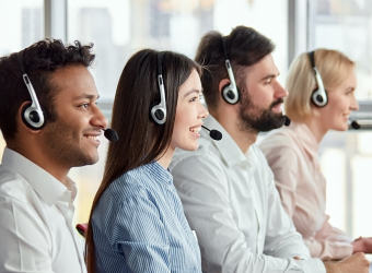 Four customer support agents wearing head sets, sitting in a row