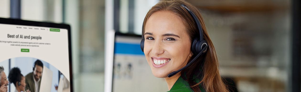 Woman with a phone headset smiling at the camera in front of a monitor displaying Gladly's site