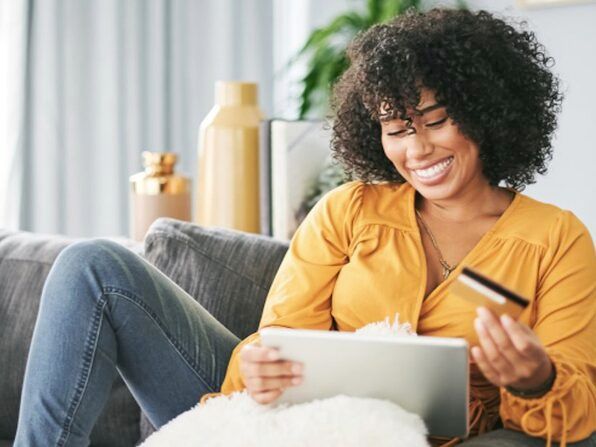 Woman holding a credit card while smiling at ipad