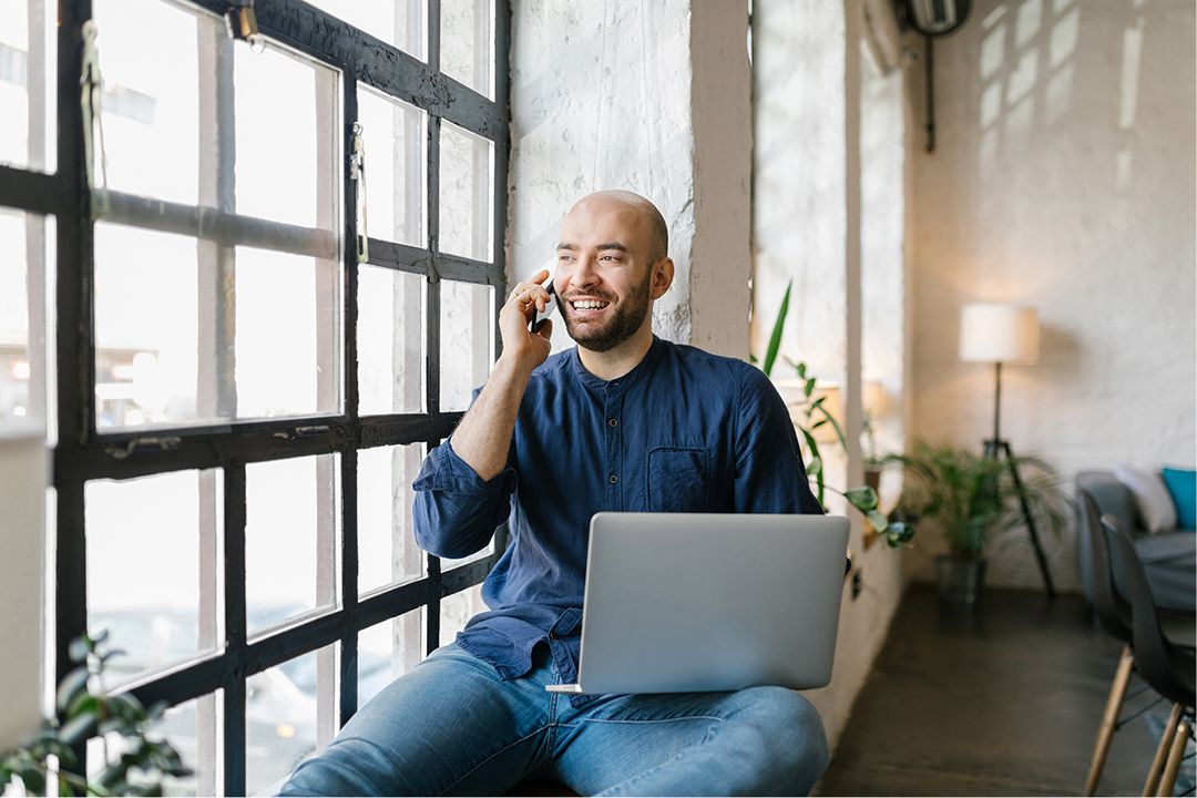man with laptop on the phone smiling