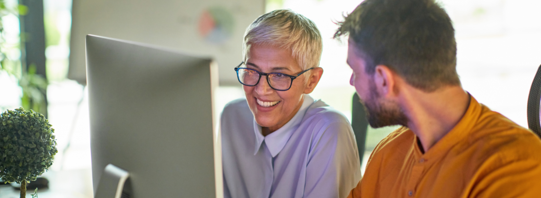 Woman and man smiling at computer in office