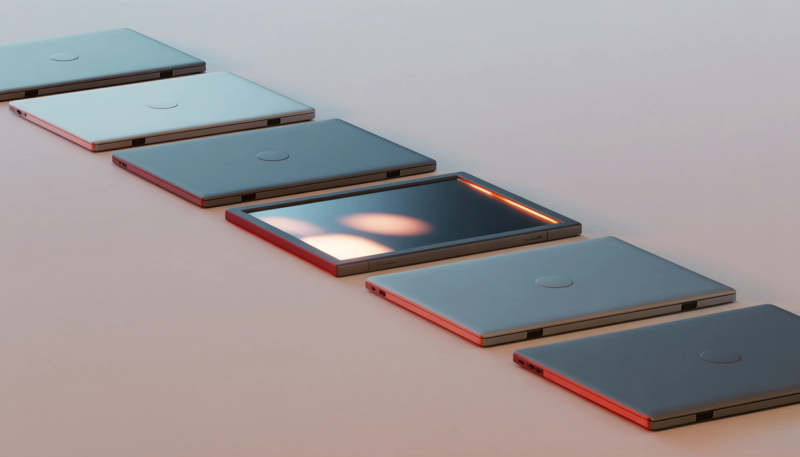 Six laptops lined up diagonally on a pale surface, five closed and one open with a lit screen