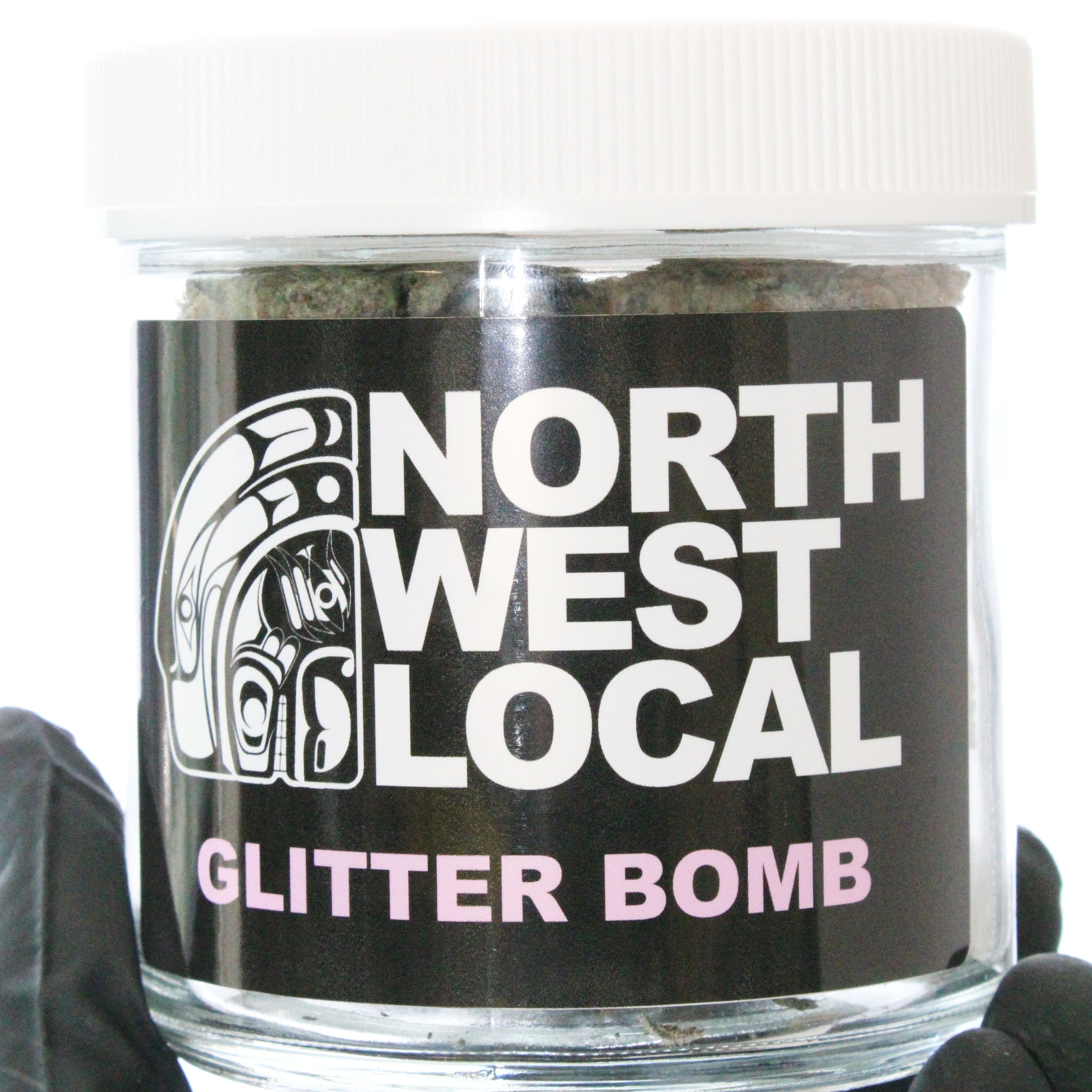 Open Northwest Local Glitter Bomb ounce jar filled with frosty purple and green buds with bright orange pistils, resting above the black label