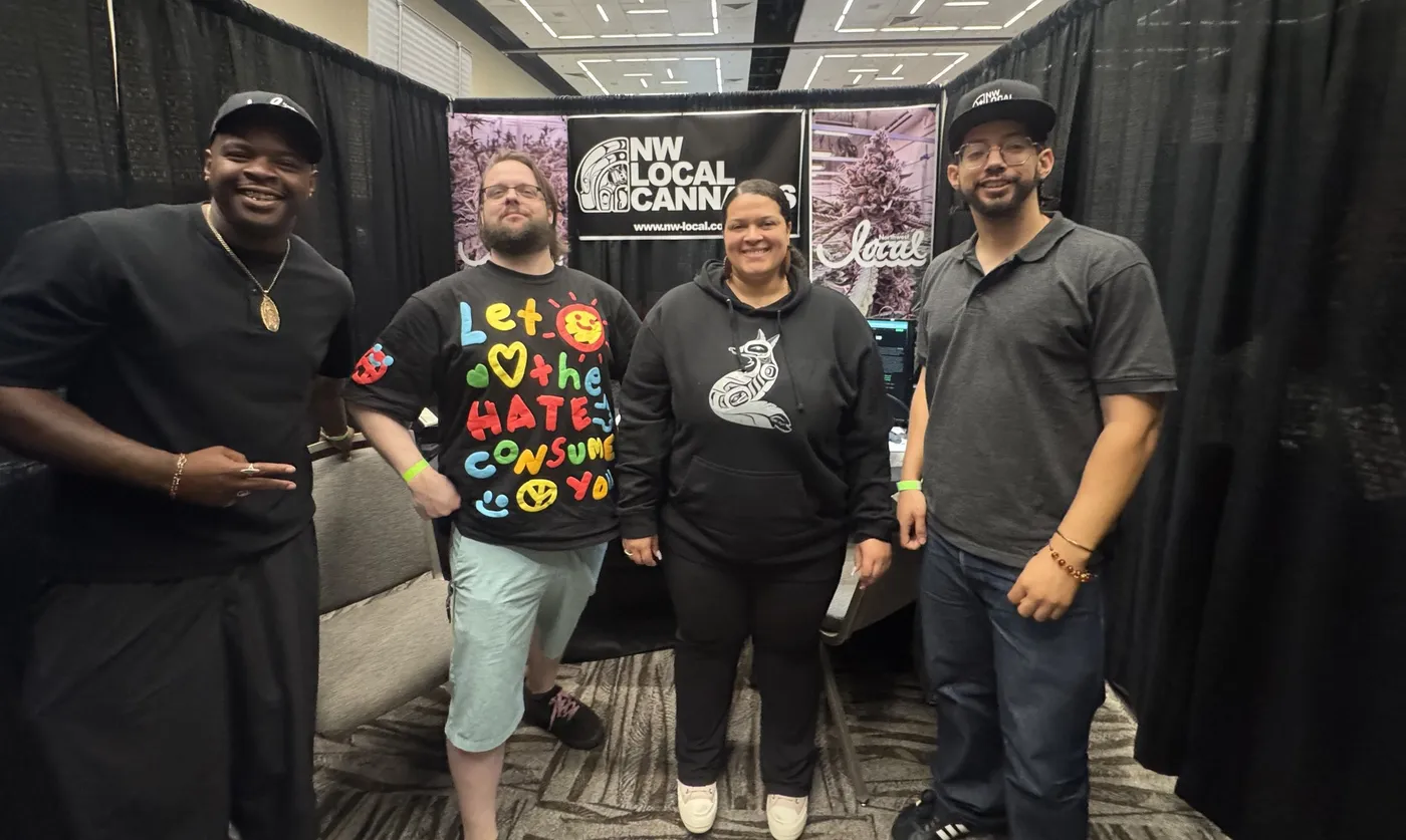 Four people standing together at the Northwest Local booth in front of the banner.