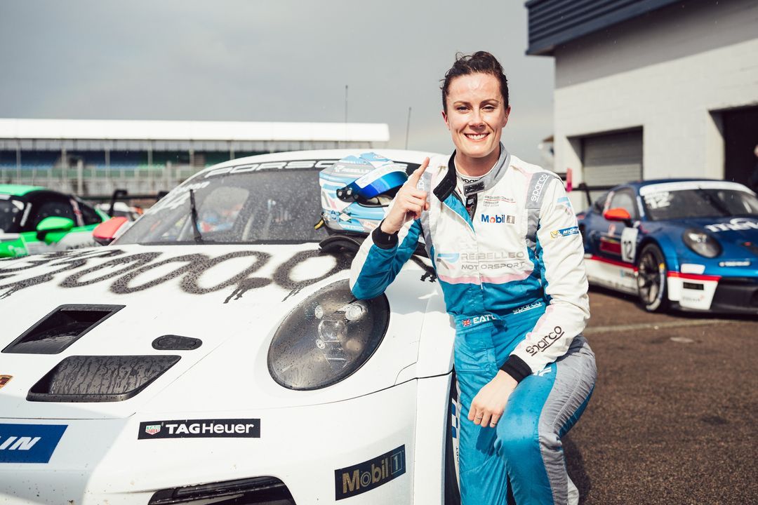 Abbie after her win at the Porsche Carrera Cup, kneeling behind her winning Porsche 911 GT3 dressed in the FAT 33 Million livery