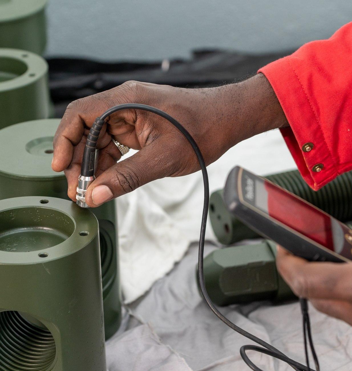 Technician measuring coating thickness on equipment