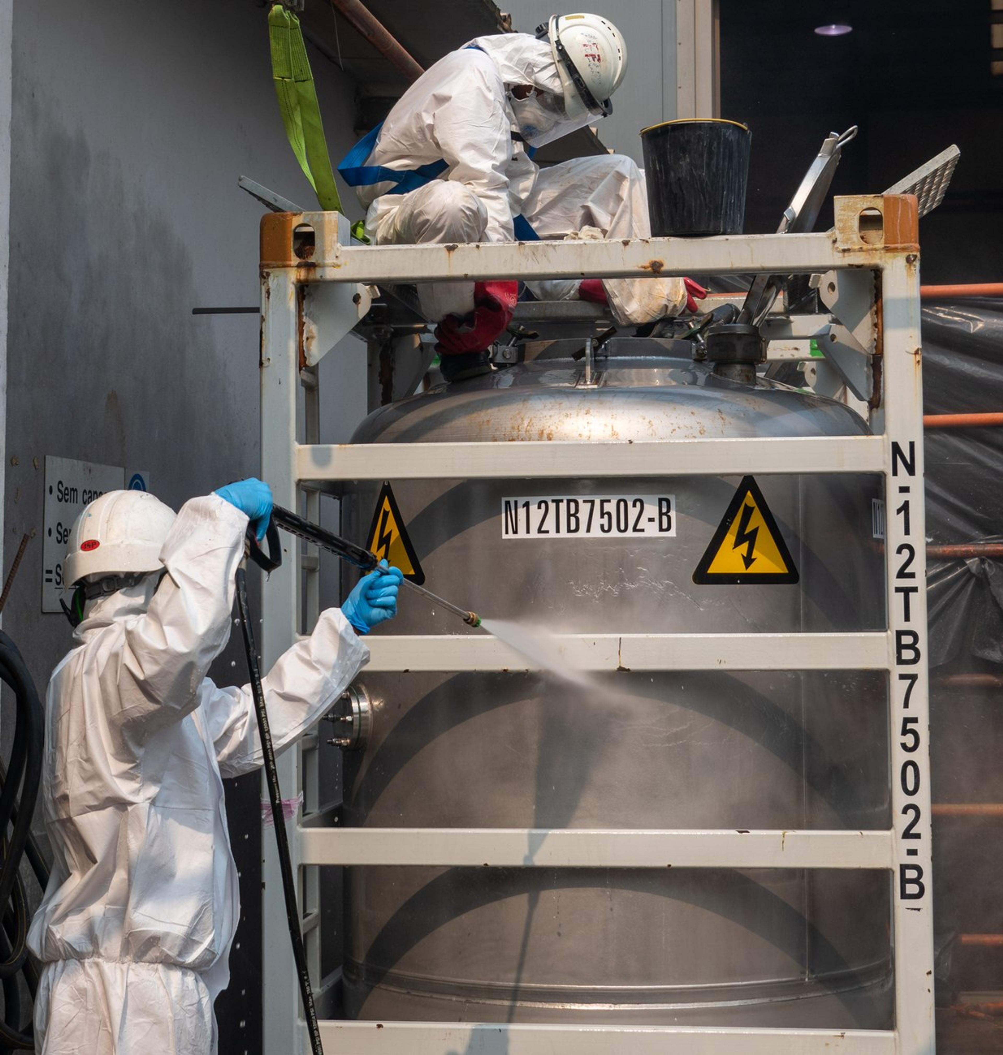 Technicians high-pressure washing a process tank