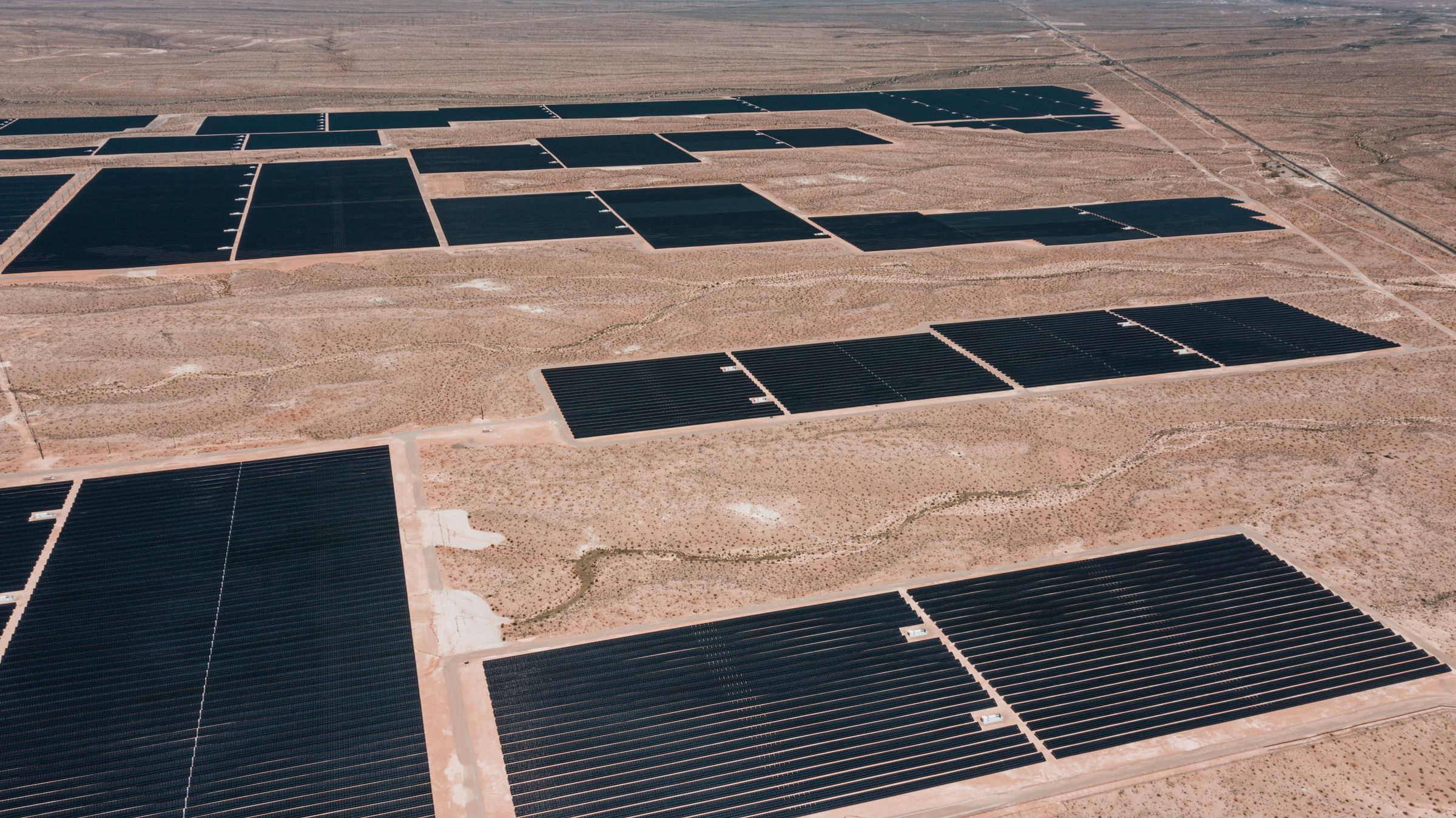 Vista aérea de un parque solar en desierto con paneles fotovoltaicos en filas