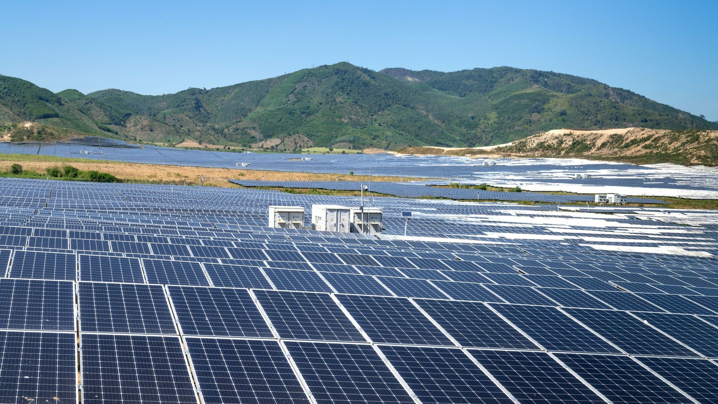 Paneles solares de un parque fotovoltaico con colinas verdes al fondo