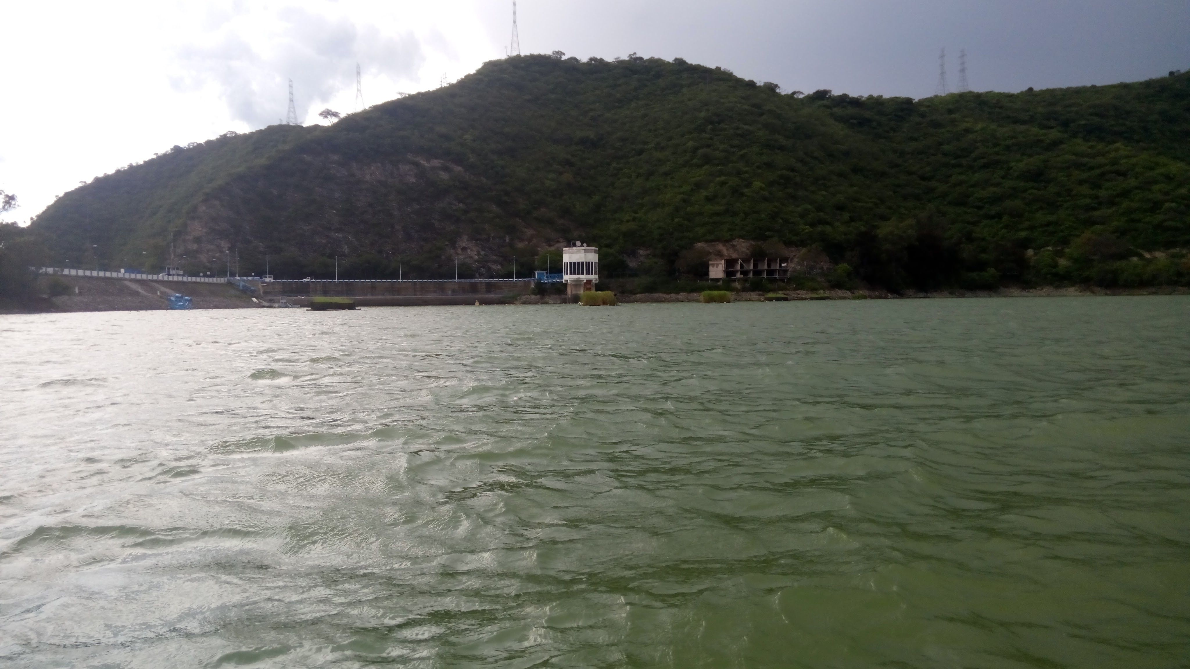 Cortina y torre de toma de la presa Valle de Bravo, del Sistema Cutzamala, con el embalse en primer plano y cerros boscosos al fondo