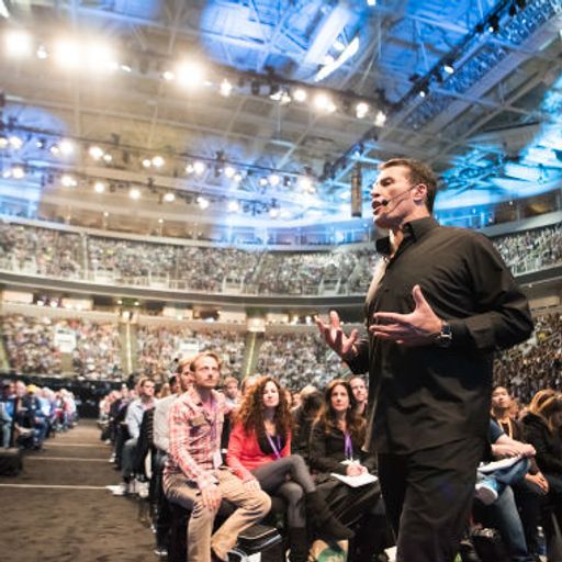 a man is giving a speech in front of a crowd in a stadium .