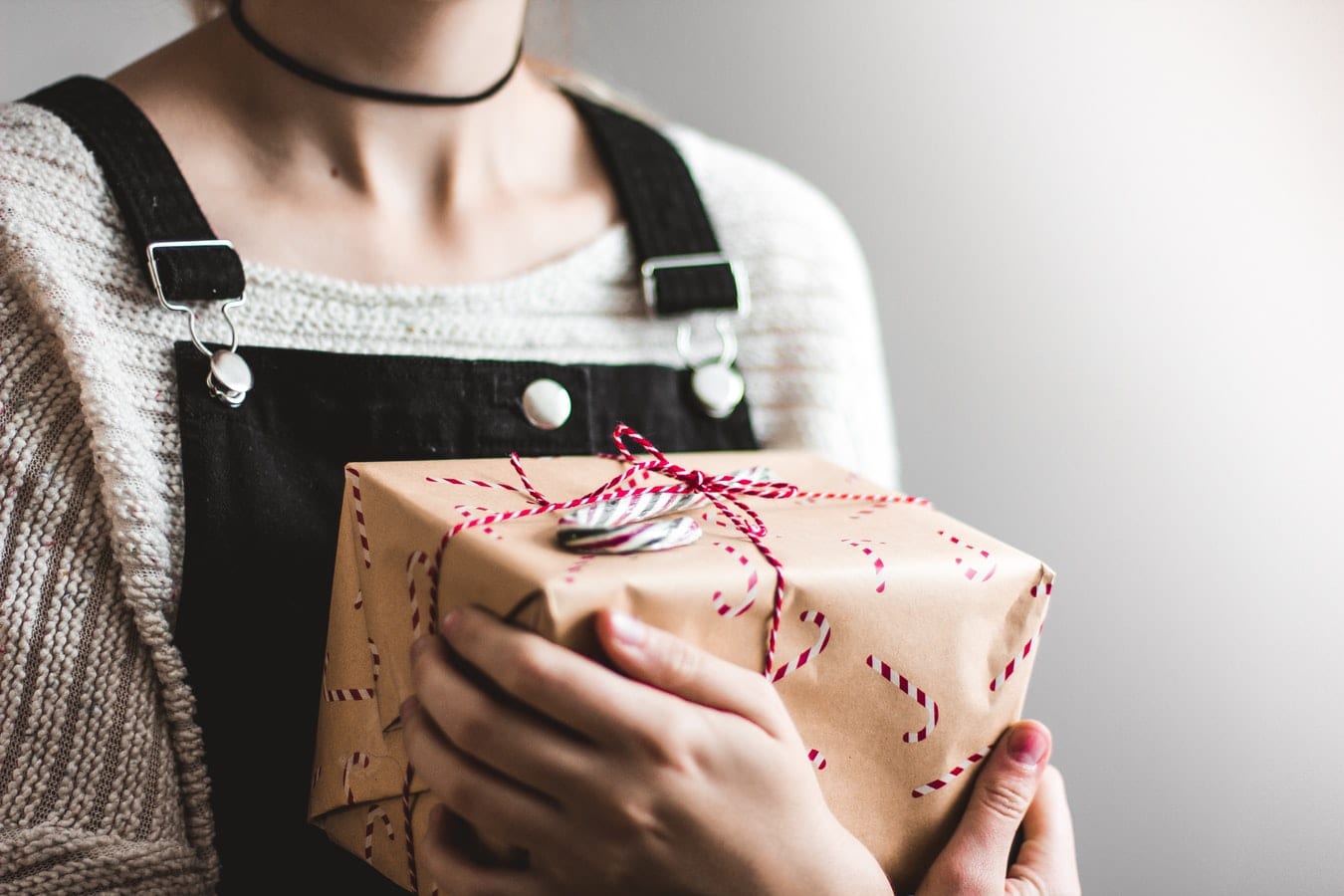a woman is holding a christmas present wrapped in brown paper .