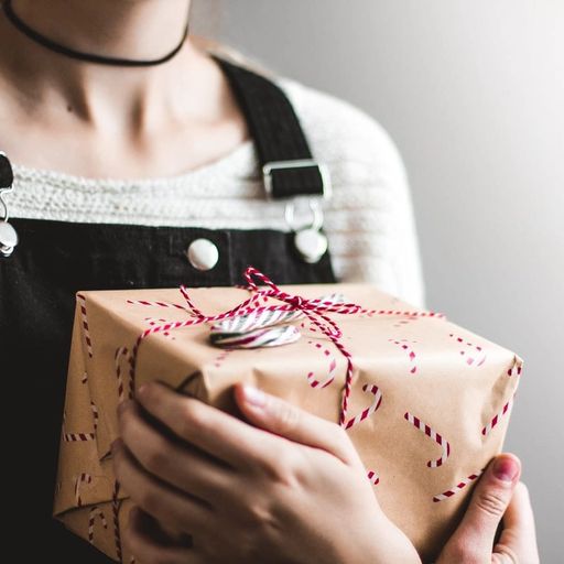 a woman is holding a christmas present wrapped in brown paper .
