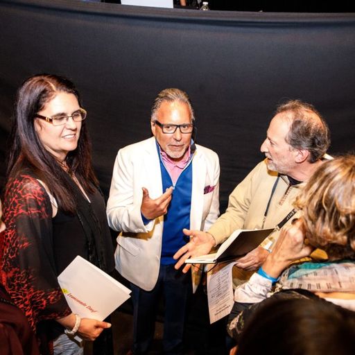 a group of people are standing around talking to each other .