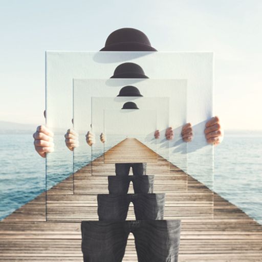 a person is holding a mirror with a reflection of a person standing on a pier .