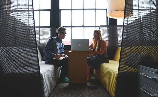 a man and a woman are sitting at a table with a laptop .