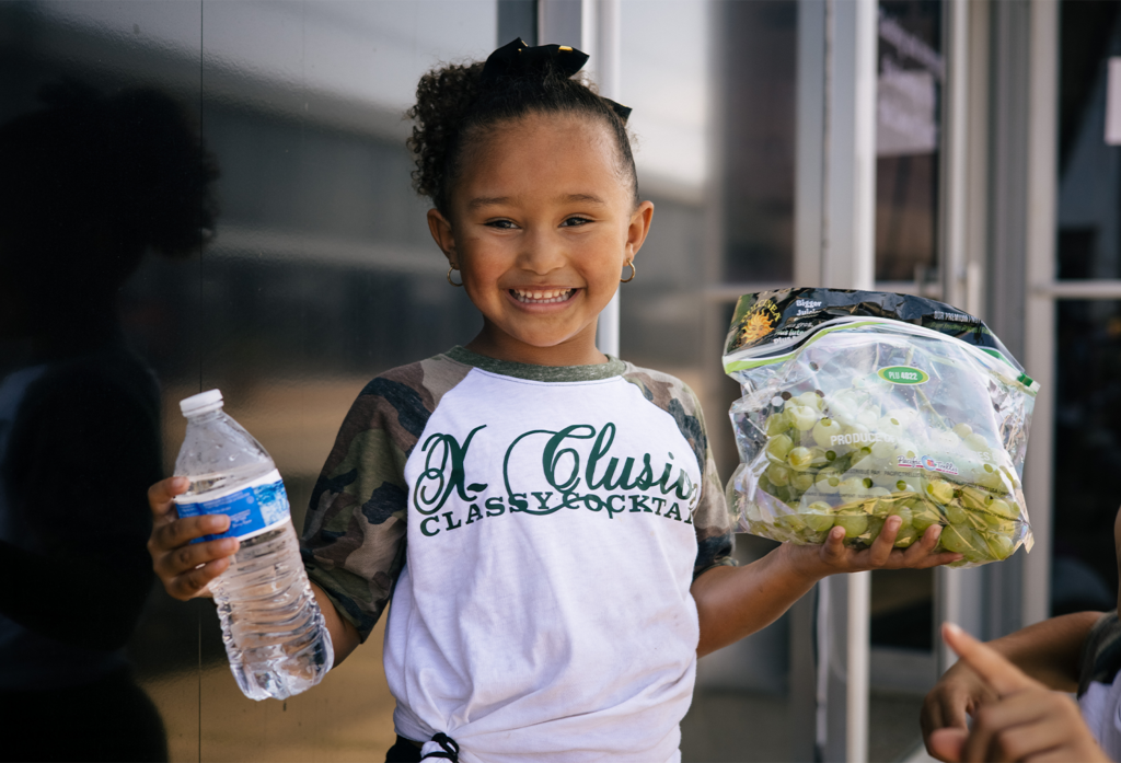 Kid holding bottle water and fruit