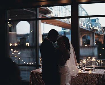 a bride and groom are dancing in front of a window at their wedding reception .