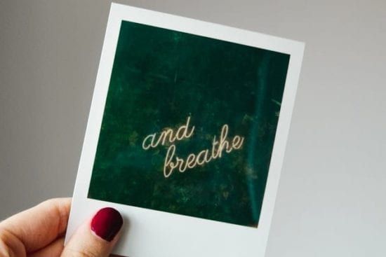 a person is holding a polaroid picture that says `` and breathe '' .