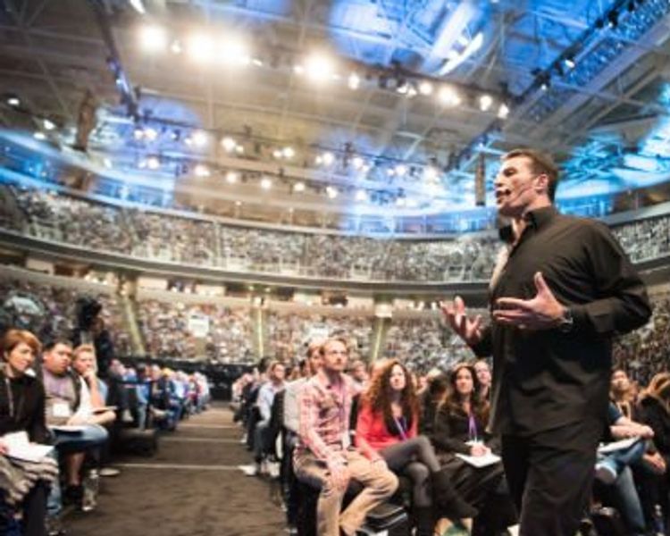 a man is giving a speech in front of a crowd in a stadium .